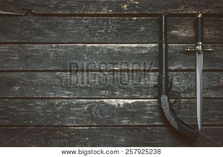 Musket Gun And Dagger Knife On Wooden Table Background With Copy Space.