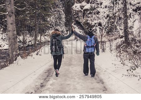 Young Couple Guy And Girl Walking In The Snow Covered Forest Among The Rocks, Retro Style Photo