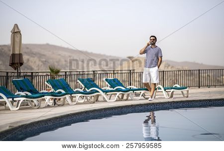 Middle Aged Arab Man On A Phone During His Summer Holiday By A Pool