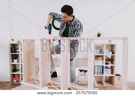 Young Man Assembling Wooden Bookshelf At Home. Wooden Bookcase. Selfmade Furniture. Man And Hobby. W