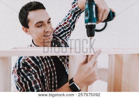 Young Man Assembling Wooden Bookshelf At Home. Wooden Bookcase. Selfmade Furniture. Man And Hobby. W
