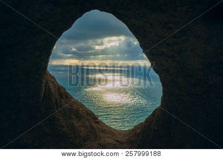 Looking At The Sunset Through The Hole In The Rocks. Close-up Of A Hole In A Rock. View To The Ocean