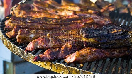 Pieces Of Meat Roasting On Metal Lattice Over Charcoal Grill At Barbecue Party Outside, Selective Fo