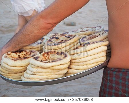 A Man Carries A Tray With Hot Khachapuri. Food Vendor On The Beach.