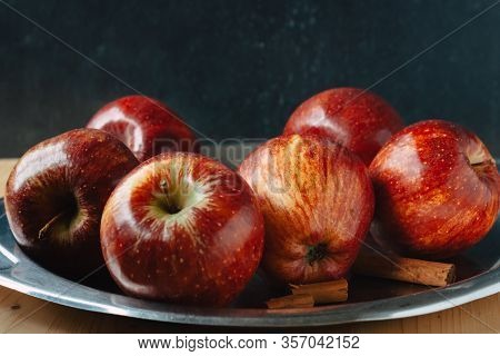 Autumn Colors. Red Apples With Some Cinnamon Sticks On A Steel Tray On Black Backgraund. Chiaroscuro