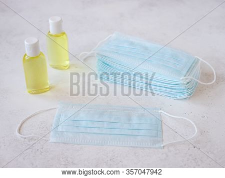 Stack Of Protective Medical Masks And A Bottle Of Liquid Antiseptic. Protection Against Coronavirus,