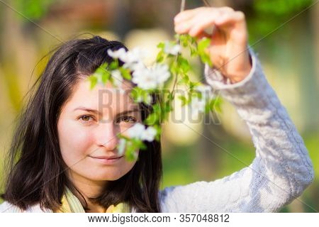 Smiling Woman Holding Twing With White Flowers. Blurred Flowers