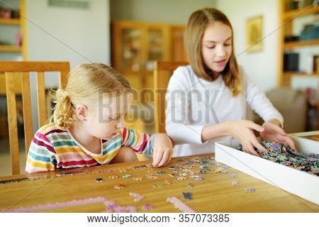 Cute Young Girls Playing Puzzles At Home. Children Connecting Jigsaw Puzzle Pieces In A Living Room