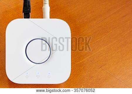 Smart Home Hub In White For Home Automation On Brown  Wooden Desktop With Copyspace.