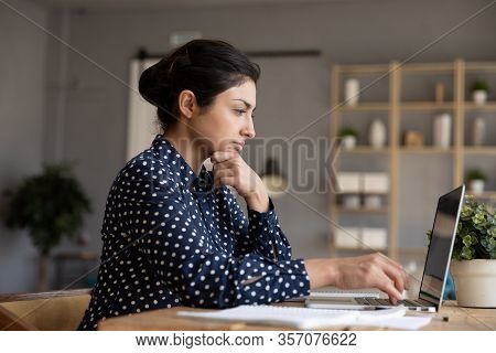 Thoughtful Indian Woman Looking At Laptop Screen, Pondering Task
