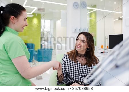 Pretty Woman Greets With Dentist Doctor. Dental Clinic Patient Sitting In A Chair Shaking Hands With