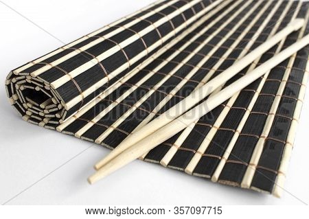 Objects For Sushi. Chinese Sticks Lie On A Black And White Partially Twisted Bamboo Wooden Rug. Side