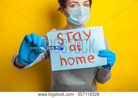 Woman In A Medical Mask With A Temperature. Holding A Thermometer In His Hands. Mild Condition Of A 
