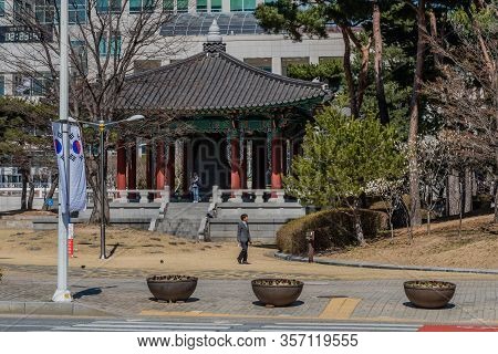 Daejeon, South Korea; March 16, 2020: Unidentified Man Walking In Front Of Ceremonial Bell In Orient