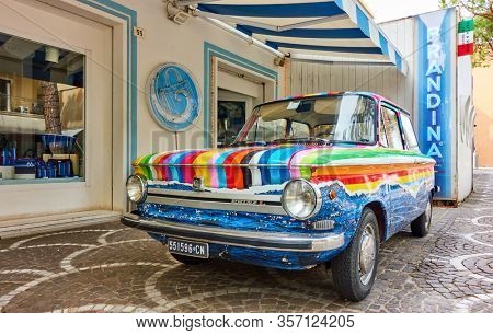 Cattollca, Rimini, Italy - February 29, 2020:  Colorful vintage car NSU Prinz L parked next to Brandina store in small italian town