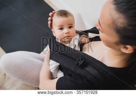 Young Mother And Her Baby In Ergo Backpack Spending Time Together At Home.