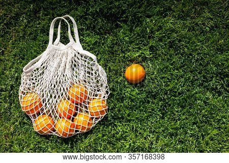 White Cotton Eco String Bag With Oranges On A Grass. Good Idea For A Picnic. Zero And Eco Waste. No 