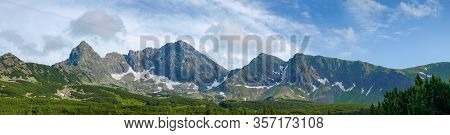 Craggy Mountain Range Against The Sky And Forest At The Foot Of The Ridge In Valley On A Foreground,