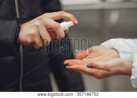 Young People Wearing Protective Masks Are Spraying Hand Sanitizer .