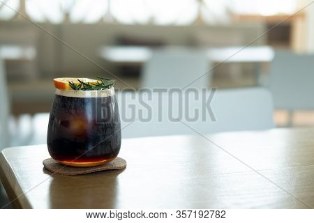 Glass Of Espresso Shot Mixed With Orange Juice On Wood Table. Refreshing Summer Drink Concept
