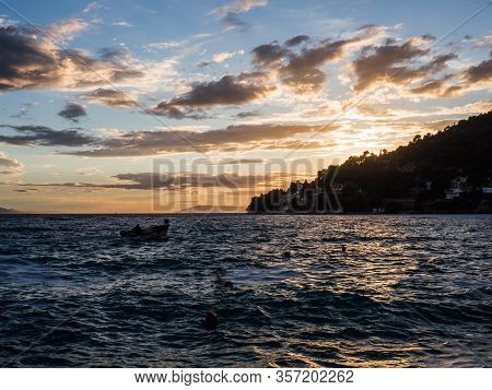 Sunset Over The Mediterranean Sea In Drvenik, Croatia And Boat Sailing To The Port.