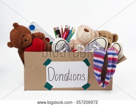 Brown Cardboard Box Filled With Soft Toys, School Supplies On White Background, Concept Of Charity A