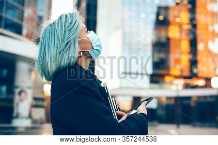 Close Up Portrait Of A Looking Up Woman With Blue Hair Wearing A Anti Flu Mask While Holding A Lapto