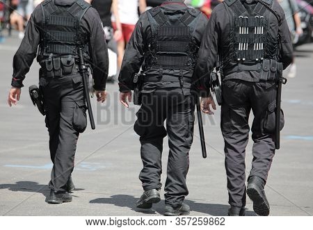 Three Policemen During The Patrol Of The City With Riot Uniform And Batons