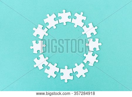 Circle made of white jigsaw puzzle pieces on blue