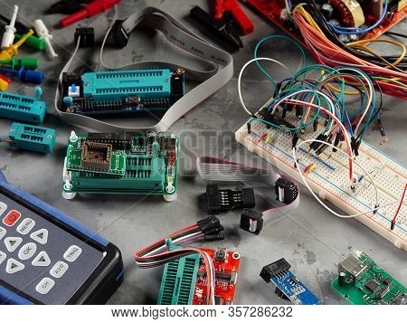 Programmers And Arduino With Peripherals And Expansion Boards Lie On A Gray Background.