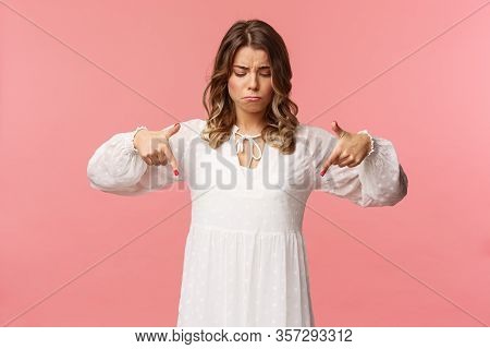 Gloomy, Jealous And Upset Cute Blond European Woman In White Trendy Spring Dress, Sulking As Pointin