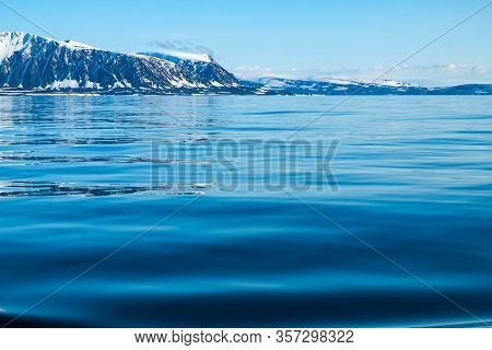 A View Of The Arctic Island From The Sea, Beyond The Ocean, You Can See The Shore, The Mountains Cov