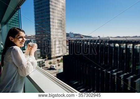 Smiling Young Business Woman Opening Up A Window For The View.hotel Room In Business/industrial Area