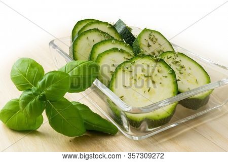 fresh green zucchini slices in glass bowl with basilicum