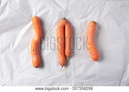 Ugly Misshapen Carrots On Craft Paper Background. Concept Of Zero Waste Production. Top View. Copy S