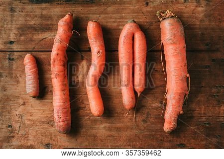Ugly Misshapen Carrots On Wooden Background. Concept Of Zero Waste Production. Top View. Copy Space.