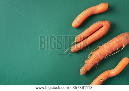 Ugly Misshapen Carrots On Green Background. Concept Of Zero Waste Production. Top View. Copy Space. 