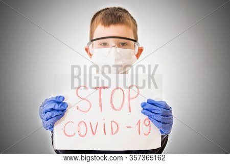 Ukraine, Kiev - March 22, 2020: A Child In Personal Protective Equipment Holding Papers Sign Stop Co