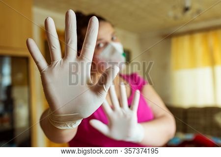 Compliance With The Rules Of Self-isolation Of A House. Young Girl In A Mask And Gloves Shows Stop H