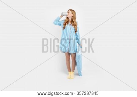 Beautiful Girl In Striped Pajamas, With A Cup In Her Hands , Drinking Coffee Or Tea In The Early Mor