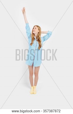 Beautiful Brooding Girl In Pajamas Holding A Pillow In Her Hands, Dreaming, Looking Away On A White