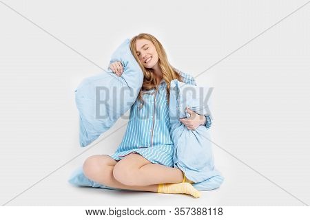 Beautiful Girl In Pajamas, Sitting On The Bed With Pillows In Her Hands, On A White Background
