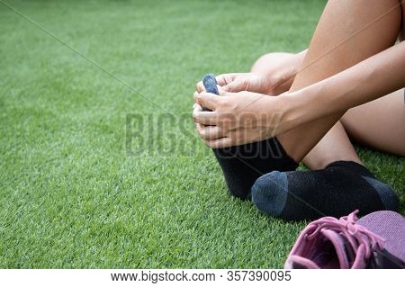 Foot Pain , The Woman Sitting On Grass. Her Hand Caught At The Foot. Having Painful Feet And Stretch