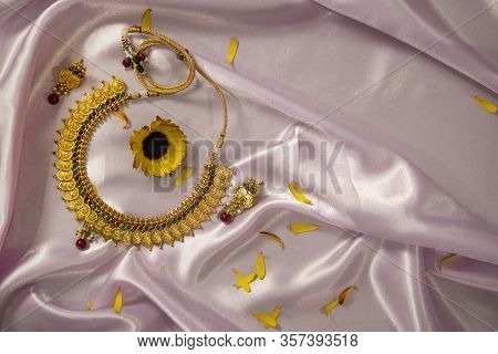 Gold Plates Silver Ginni Jewelery On Baby Pink Silk Cloth Background