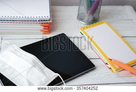 Stay At Home Concept. Pc Tablet, Medical Mask, Books And Markers On Wooden Table. Distanse Education