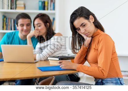 Lonely Young Adult Woman With Group Of Students At Classroom Of School