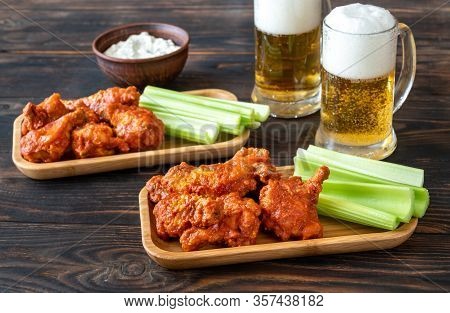 Buffalo Wings With Celery Stalks, Blue Cheese Dip And Glass Mugs Of Beer