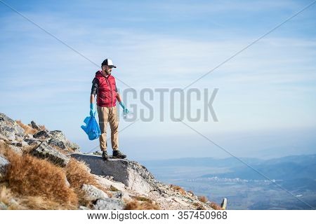 Man Hiker Picking Up Litter In Nature In Mountains, Plogging Concept.