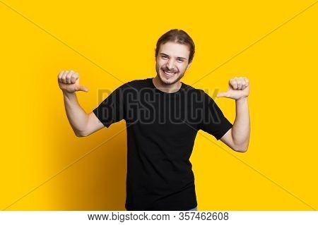 Confident Caucasian Man With Beard And Long Hair Pointing To Him While Posing On A Yellow Background