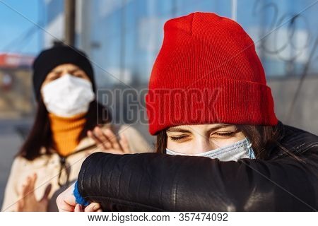 Young Girl Coughs In An Elbow To Cover. Two Girls Waiting For A Bus. Woman Leans Back From A Sneezei